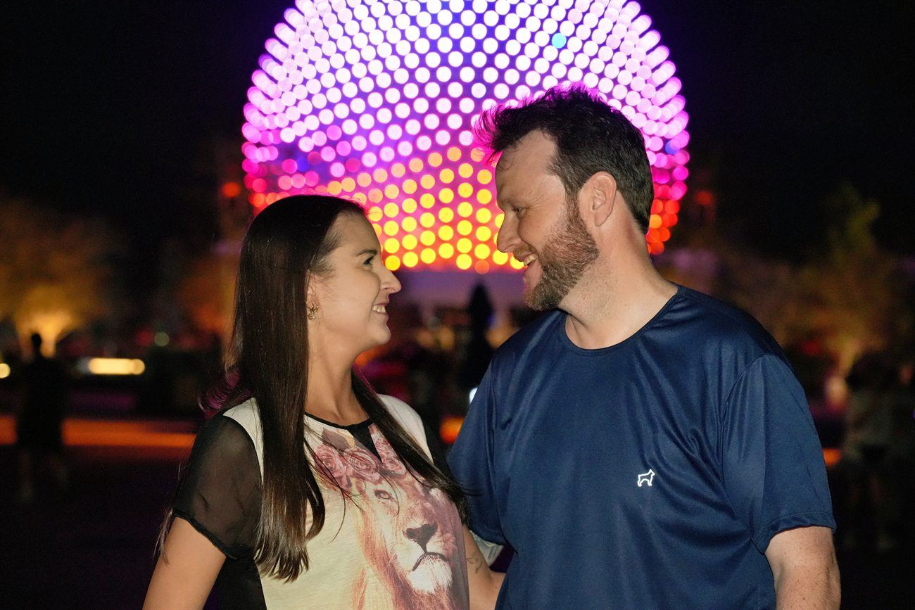 Casal em frente à esfera iluminada do Epcot, à noite